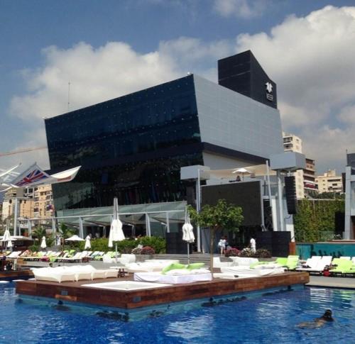 une piscine avec des chaises longues blanches et un bâtiment dans l'établissement Veer Luxury Boutique Hotel & Beach Club, à Jounieh