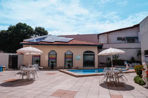 un patio avec des chaises et des parasols à côté d'une piscine dans l'établissement Costa Atlantico Hotel, à São Luís