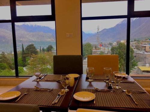 a table with glasses and plates on it with a view at Avari Xpress Gilgit in Gilgit