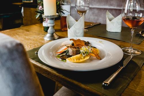 a plate of food on a table with wine glasses at Hotel Sommerhof in Gosau