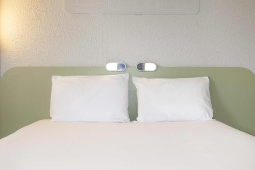 - un lit avec deux oreillers et deux lumières dans l'établissement ibis budget Goussainville Charles de Gaulle, à Goussainville