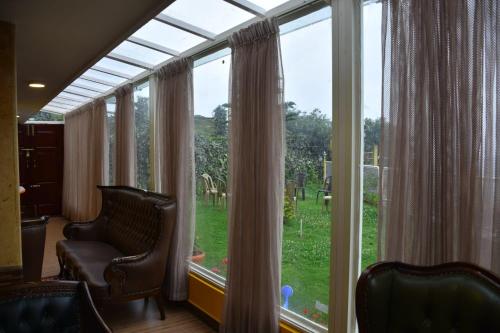 Habitación con una gran ventana con sillas delante. en Glen Premium Villa By LexStays, en Ooty