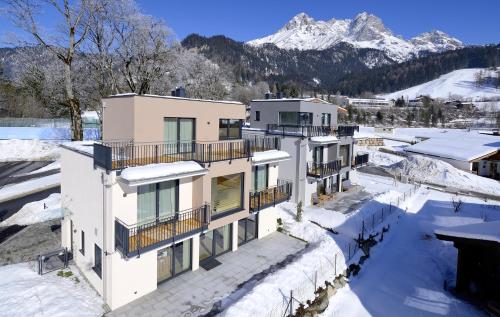 una casa nella neve con montagne sullo sfondo di dasLichtenberg westside a Saalfelden am Steinernen Meer