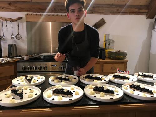 un homme debout dans une cuisine avec plusieurs assiettes de desserts dans l'établissement Chambre d'hôtes Carélie et Laponie, à Orbey