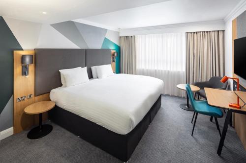 グロスターにあるHoliday Inn Gloucester - Cheltenham, an IHG Hotelのベッドとデスクが備わるホテルルームです。