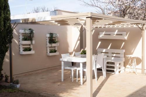 eine weiße Pergola auf einer Terrasse mit einem Tisch und Stühlen in der Unterkunft Emotions in Fiumicino