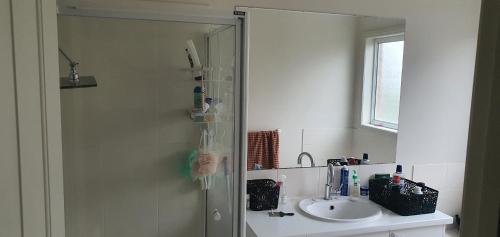 a bathroom with a shower with a sink and a mirror at Home stay in Wyndham Vale