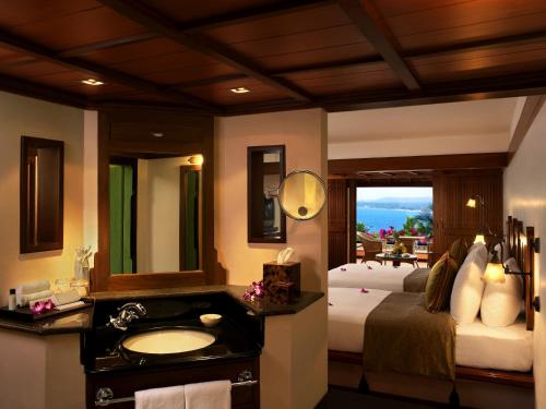 The Leela Kovalam, A Raviz Hotel في كوفالام: حمام فيه سرير ومغسلة ومرآة