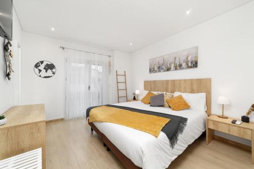 una camera da letto con un grande letto bianco con cuscini arancioni di LUMO Apartment Fátima a Fátima