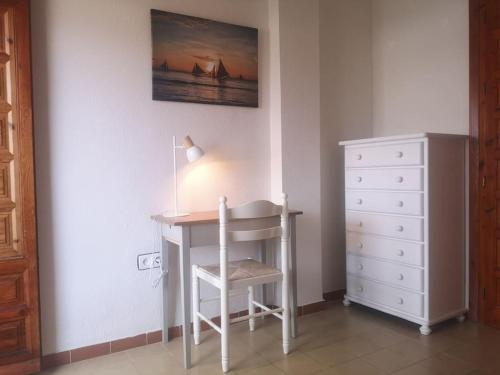 einen Schreibtisch mit einem Stuhl und einer Lampe neben einer Kommode in der Unterkunft Apartamento con la playa a 200 metros in Granada