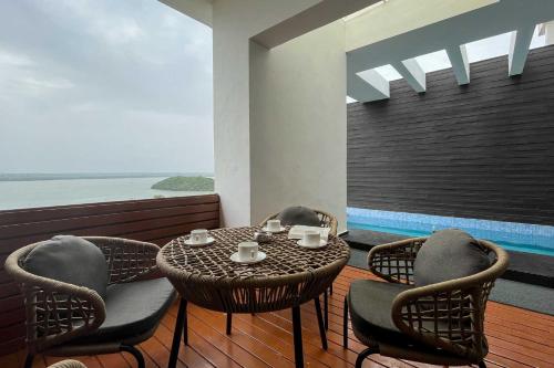 uma mesa e cadeiras numa varanda com vista para o oceano em StayVista at Tarika's Seascapes with Pool & Home Theatre em Dabolim