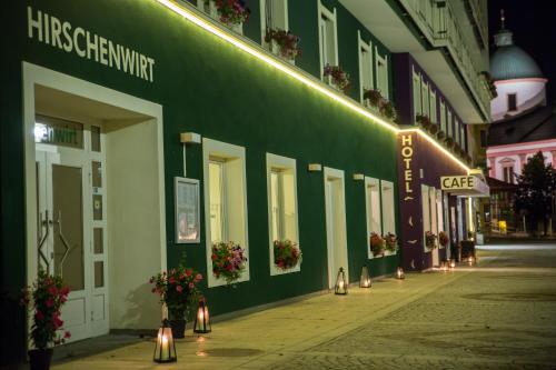 un bâtiment vert avec des lumières sur le côté d'une rue dans l'établissement AKTIVHOTEL Weisser Hirsch, à Mariazell