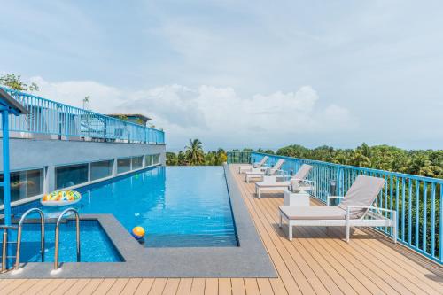 a swimming pool with lounge chairs on a deck at De Mandarin Goa in Candolim