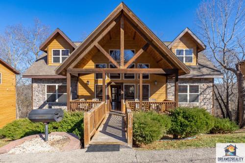 une maison avec un toit en gambrel et une terrasse couverte dans l'établissement Forest Heights Lodge - 6BR - Pool Table - Near Silver Dollar City - FREE TICKETS INCLUDED, à Branson