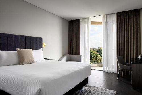 a bedroom with a large bed and a large window at Crowne Plaza Sydney Burwood by IHG in Sydney