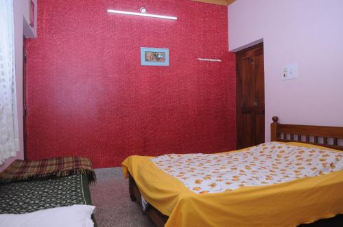 una camera con una parete rossa e un letto di Misty Retreat (Pragati House) a Madikeri