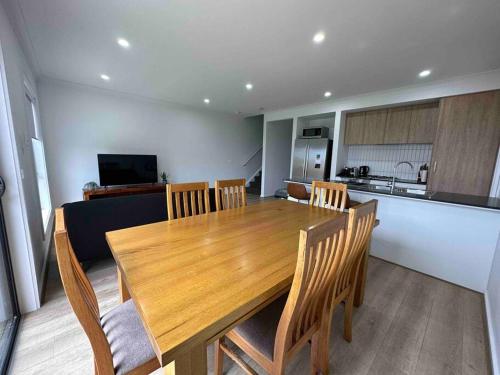 a dining room table with chairs and a kitchen at Wonderful Jubilee Estate House in Wyndham Vale