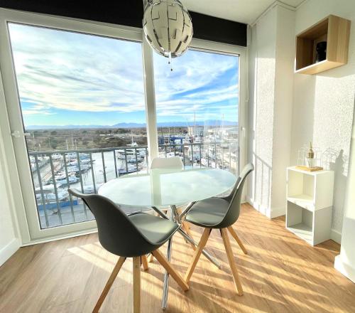 a dining room with a table and chairs and a large window at Holidays Penthouse vues panoramiques sur le Port naval,un séjour élégant assuré " Wifi Pàrquing gratuït in Roses