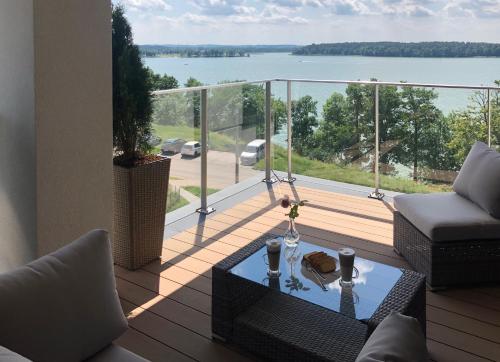 einen Balkon mit einem Tisch und Blick auf das Wasser in der Unterkunft Apartament Złota Brama in Lyck