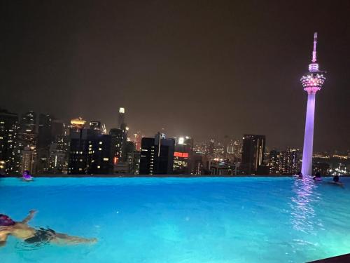 una mujer nadando en la piscina con vistas a la torre Seoul en The Platinum KLCC By Sky Pool, en Kuala Lumpur