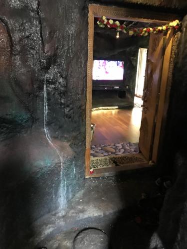 una porta aperta per una camera con TV in una grotta di Rai’s Coorg Cave House a Madikeri