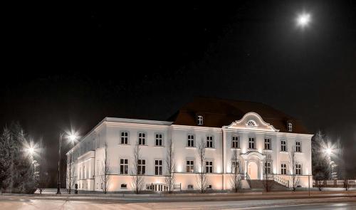 a large white building at night with lights at Adler in Swarzędz