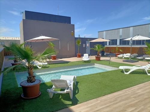 a pool with chairs and a palm tree next to a building at Hotel BESTPRICE Alcalá in Madrid