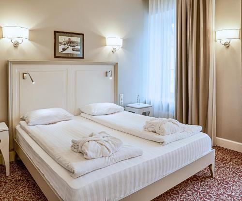 una camera da letto con un grande letto bianco con asciugamani di Ratonda Centrum Hotels a Vilnius