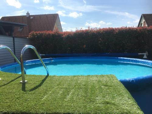 una piccola piscina blu con un prato verde accanto a una casa di DieLangthalers Exklusive Oase a Seiersberg