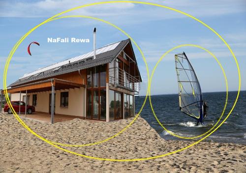 ein Haus am Strand mit Windsurfer davor in der Unterkunft Noclegi NaFali Rewa in Rewa