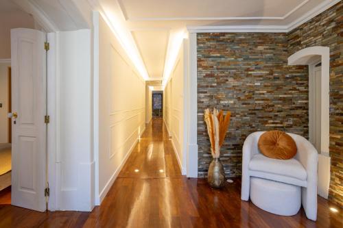 a hallway with a chair and a brick wall at Charming Apt in Historic House in Coimbra