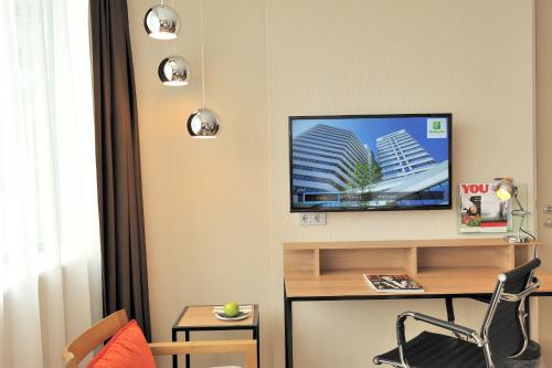 uma sala de estar com uma televisão na parede em Holiday Inn Amsterdam - Arena Towers, an IHG Hotel em Amesterdão