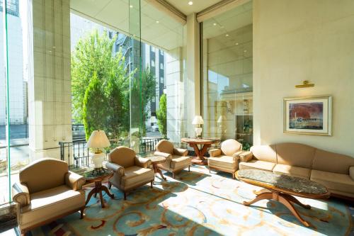 a lobby with couches and chairs and a large window at KOKO HOTEL Nagoya Sakae in Nagoya