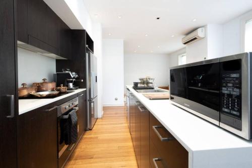 cocina con armarios negros y encimera blanca en Eggie's Nest - Luxurious City Apartment, en Sídney