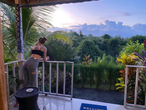 uma mulher de pé numa varanda com vista para a selva em The Pancor Jungle Resort em Nusa Penida