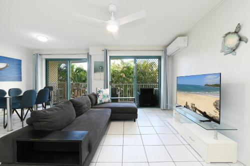 a living room with a couch and a flat screen tv at Lindomare Apartments in Caloundra