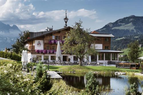 un hôtel avec un lac en face d'un bâtiment dans l'établissement Hotel Chalets Grosslehen, à Fieberbrunn