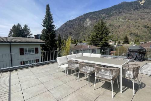 patio z białym stołem i krzesłami oraz górami w obiekcie Terrace Vista Interlaken w mieście Interlaken