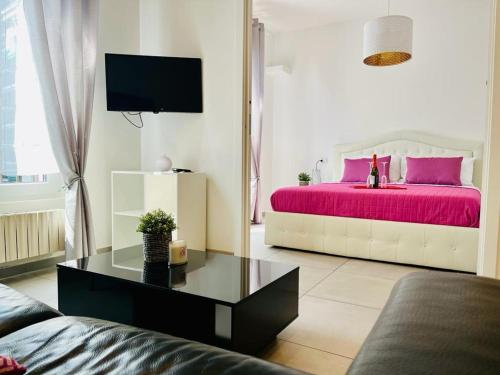 a living room with a bed with pink sheets at Grazioso bilocale in centro storico in Verbania