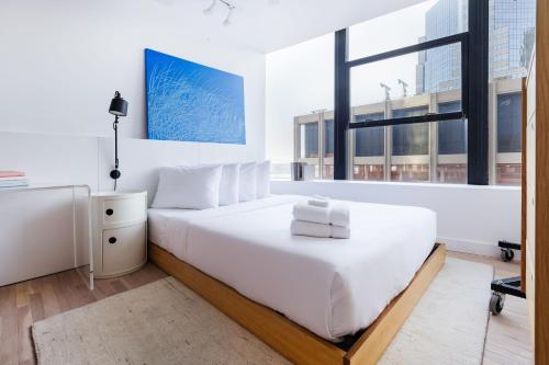 a white bedroom with a bed and a window at Placemakr Wall Street in New York