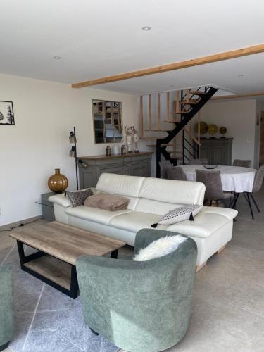 a living room with a couch and a table and chairs at Charmant chalet, spacieux, proche du lac, vue sur la montagne in Gérardmer