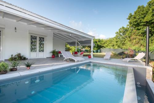 een zwembad met stoelen en een huis bij Villa Rosette in Sainte-Anne