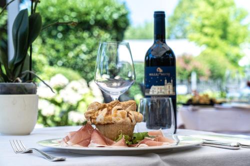 um prato de comida numa mesa com uma garrafa de vinho em Hotel Ristorante Vecchia Riva em Varese