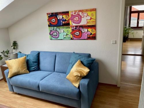 eine blaue Couch in einem Wohnzimmer mit einem Gemälde an der Wand in der Unterkunft Charmante Dachgeschoss Wohnung in Leipzig