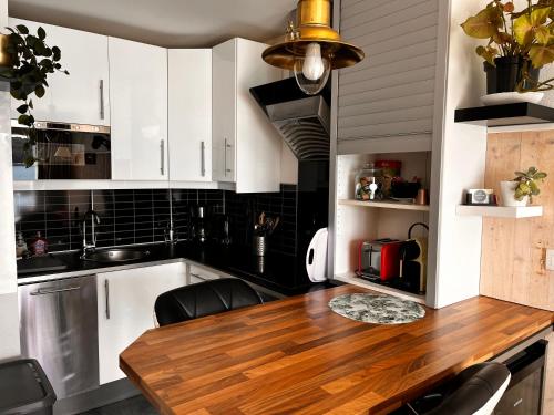 a kitchen with white cabinets and a wooden table at Une terrasse sur la mer in Crozon