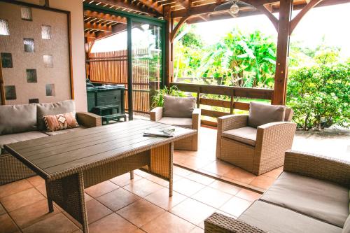 an outdoor patio with a wooden table and chairs at Villa Le Colonial Zen - T4 à 5 mn Aéroport in Sainte-Marie