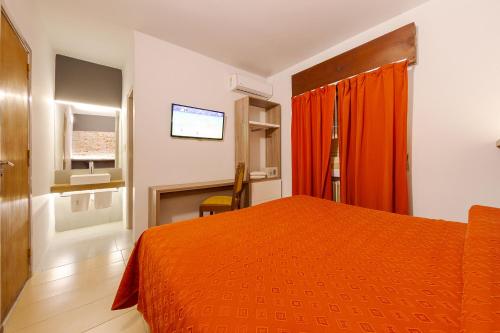 - une chambre avec un lit orange et une télévision dans l'établissement Hotel El Condado, à Villa Carlos Paz