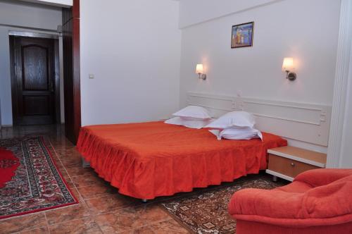 a bedroom with a red bed and a chair at Hotel Lido in Mamaia