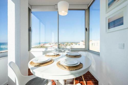 uma sala de jantar branca com uma mesa e uma grande janela em Ria Beach House em Faro