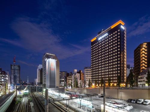 APA Hotel Yamanote Otsuka Eki Tower في طوكيو: أفق المدينة في الليل مع مبنى طويل